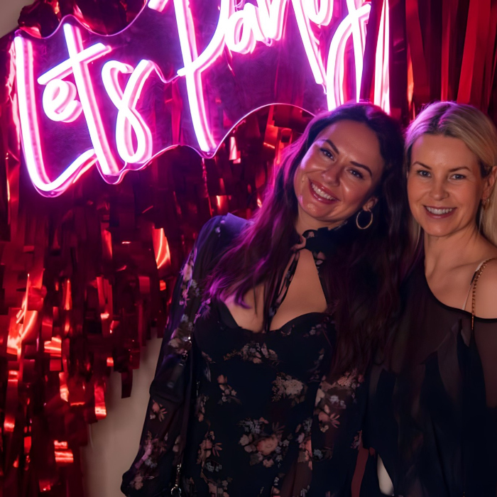 Pink Custom Neon® Let's Party sign on streamer wall