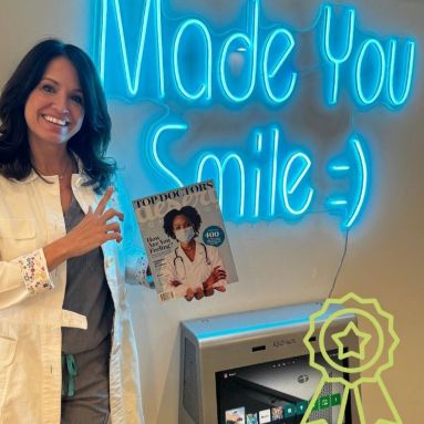 Dentist holding a magazine with a large blue Made You Smile Custom Neon® sign in the background @saxeortho