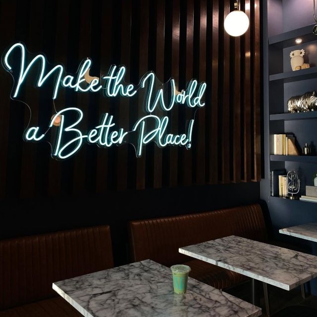 The Ivy House and Learfield green LED neon sign set into a greenery wall behind a hanging swing seat