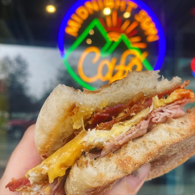 Multicolored Custom Neon® logo sign in front window @midnightsuncafe