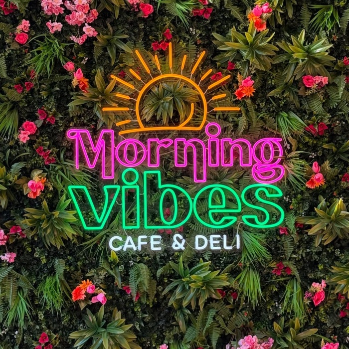 multicolored Custom Neon® sign on grass wall @morningvibescafeco