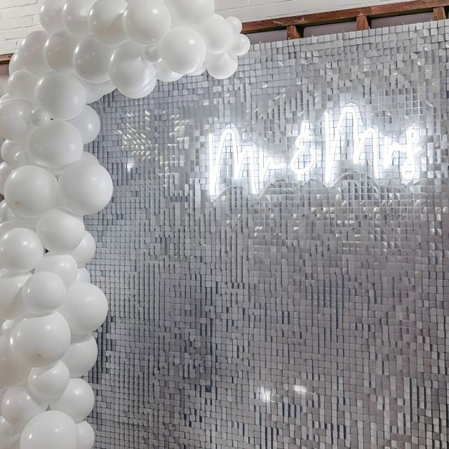 White Custom Neon® Mr and Mrs wedding sign on a silver shimmer wall with a balloon garland styled by @raspberrycraftsandevents