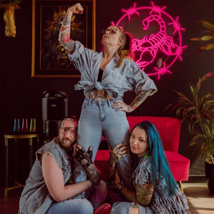 Dark pink LED Custom Neon® artwork of a scorpion in a circle of barbed wire on a dark wall behind the tattoo artists @neonscorpiontattoo studio