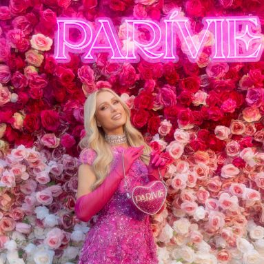 Pink Parivie sign by Custom Neon® on a rose wall with Paris Hilton in the foreground @parivie @parishilton