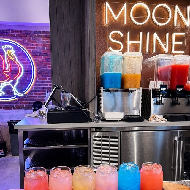 Custom Neon® Moonshine sign and rooster logo behind a drink station at the Chef Art Smith Reunion restaurant on Navy Pier