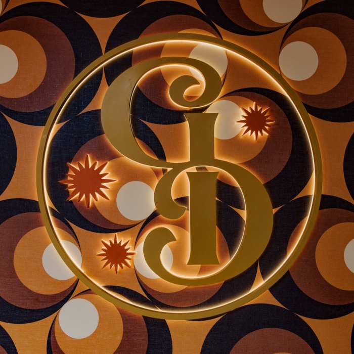 Round reverse lit logo with GD in gold colored stainless steel and red colored stainless steel stars made by Custom Neon®