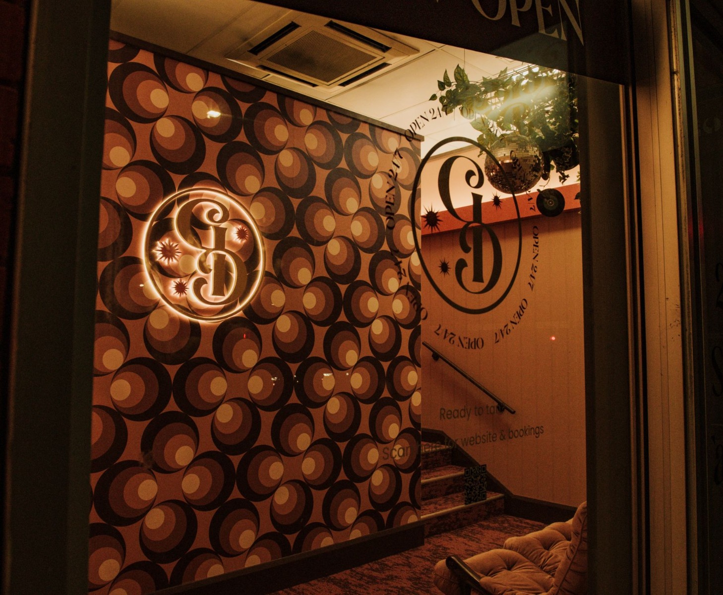 Gold colored stainless steel reverse lit logo made by Custom Neon® on a 70s inspired wall in the Golden Days tanning salon as seen through the salon's front window