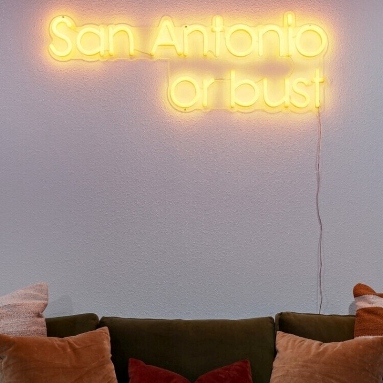 San Antonio or Bust orange LED Custom Neon® sign in a living room wall @hometeamvacationrentals