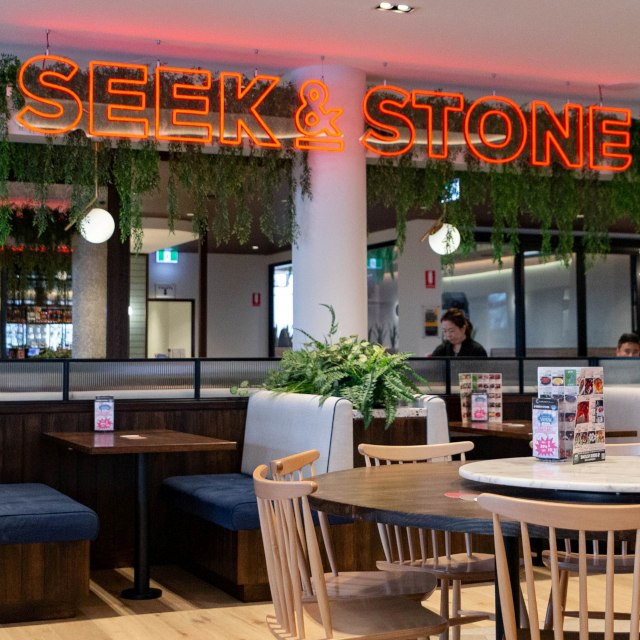 Orange Custom Neon&reg; restaurant sign suspended from the ceiling @seek&stone