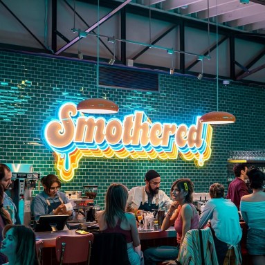 Multicolored restaurant name sign feature wall by Custom Neon® @smothered