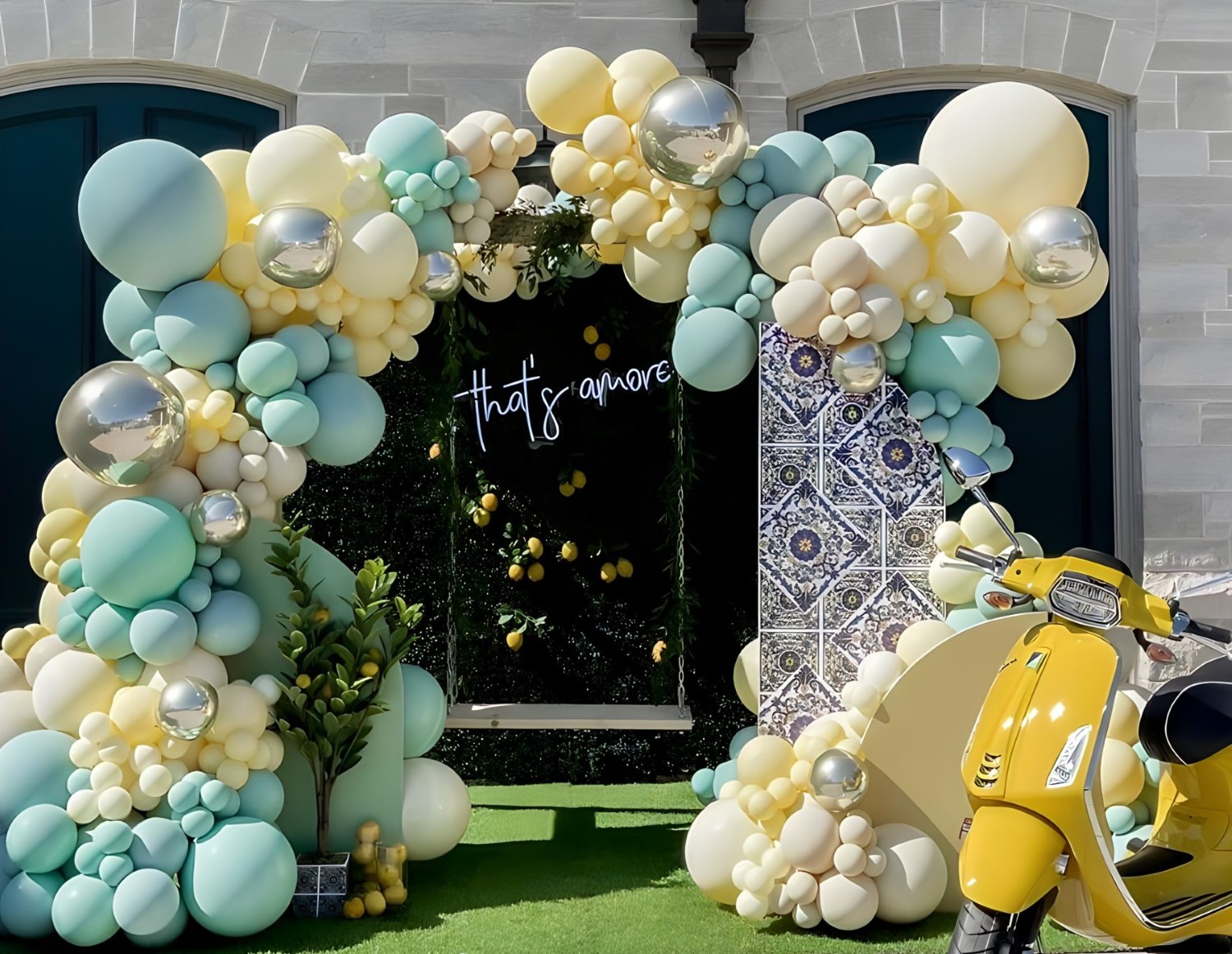 Custom Neon® white That's Amore sign on a greenwall behind a wooden swing surrounded by a yellow and green balloon arch - event decor by @decorandfiesta