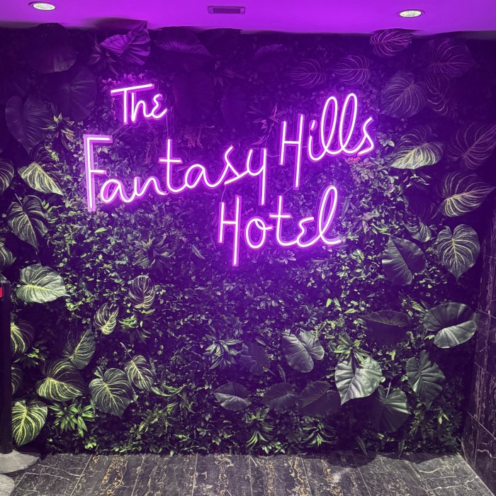 The Fantasy Hills Hotel Custom Neon® selfie station sign on a grass wall at the Fantasy Hills Hotel in Edmonton Mall