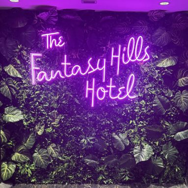 The Fantasy Hills Hotel Custom Neon® selfie station sign on a grass wall at the Fantasy Hills Hotel in Edmonton Mall