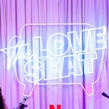 The Love Seat podcast logo in pink and blue LED neon at a Netflix live event