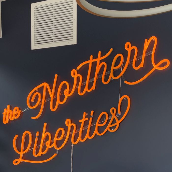 The Northern Liberties orange Custom Neon® office sign in a fancy script font @cohatch