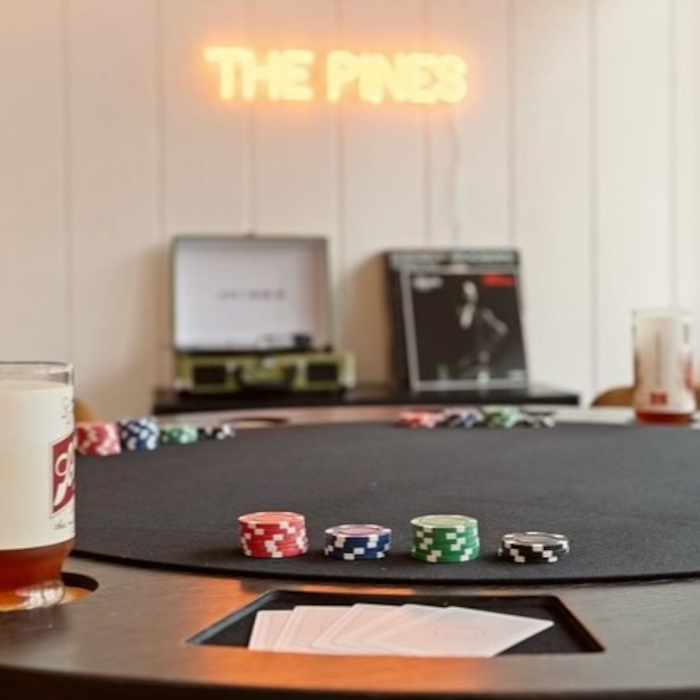 The Pines orange LED Custom Neon® airbnb sign on a white wood pannelled wall @thepinesatlakenaomi