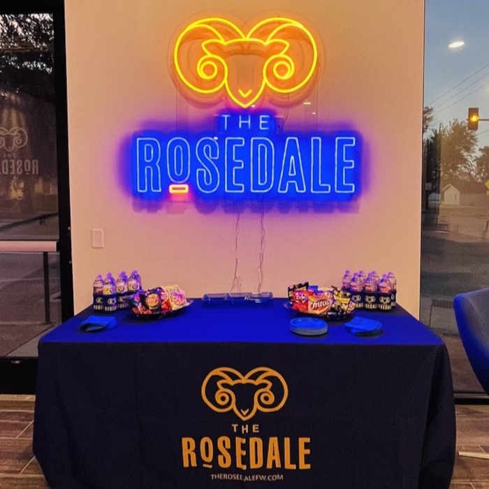 The Rosedale Fort Worth custom LED neon logo sign with an orange ram above a blue wordmark at a venue snack table