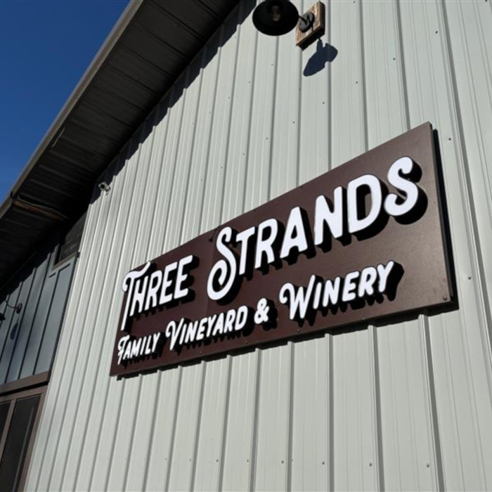 Three Strands Winery white front lit channel letter sign on a corrugated metal wall