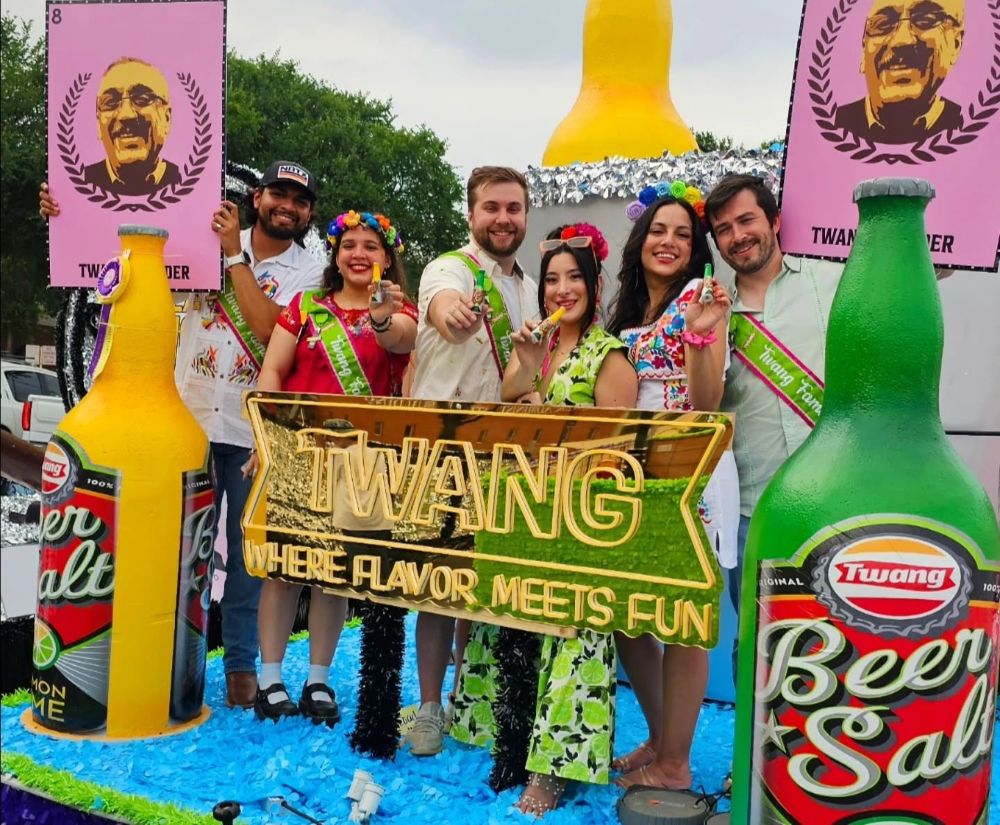 Twang team in flower crowns behind their gold mirrored Where Flavor Meets Fun LED neon sign at a San Antonio fiesta event