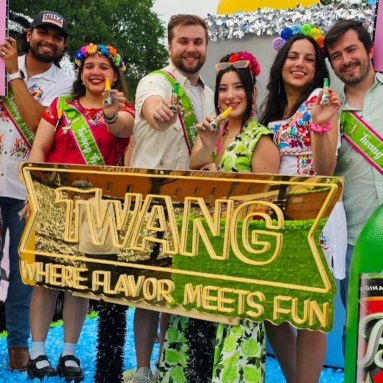 Twang team in flower crowns behind their gold mirrored Where Flavor Meets Fun LED neon sign at a San Antonio fiesta event