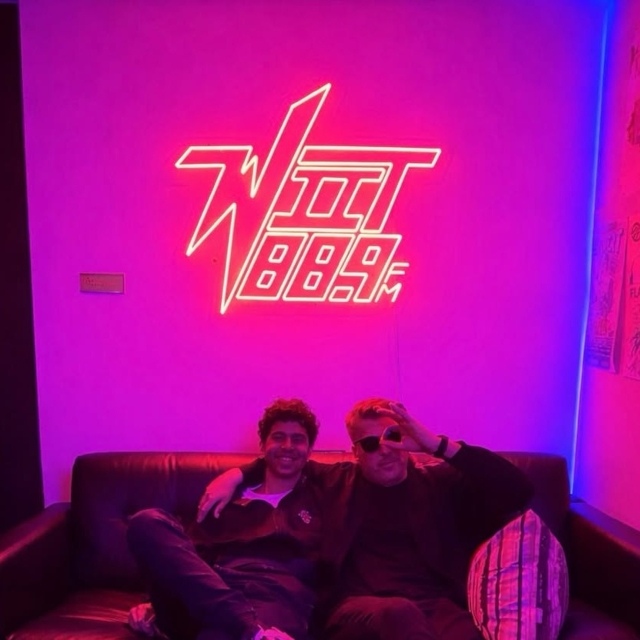 WIIT 88.9FM Custom Neon® sign glowing pink above a couch in a Chicago radio station